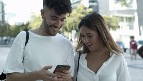 Smiling-young-couple-looking-at-smartphone